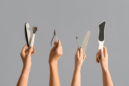 Female hands with supplies for pedicure on gray backgroundの写真素材