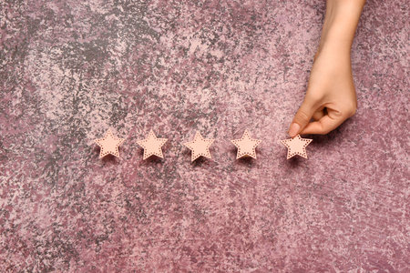 Female hand with five stars rating on pink grunge background. Customer experience concept