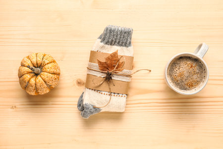 Warm socks with cup of coffee and pumpkin on beige wooden backgroundの写真素材