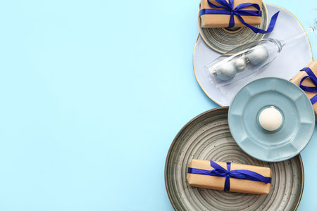 Beautiful table setting with Christmas balls and gift boxes on blue backgroundの写真素材