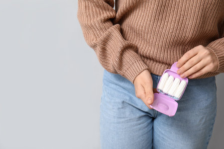 Young woman with tampon box on light background, closeupの写真素材