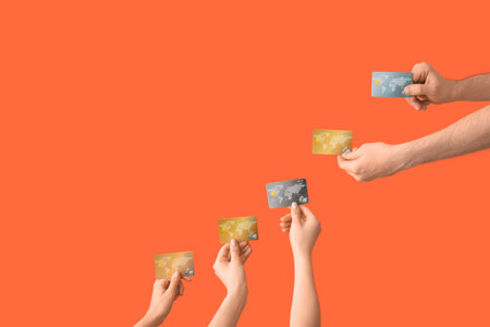 Female hands with credit cards on orange backgroundの写真素材