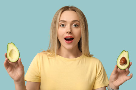 Surprised young woman with avocado on blue background