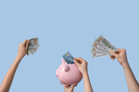 Female hands with piggy bank, credit card and money on blue backgroundの写真素材