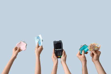 Female hands with payment terminal, wallets and money on gray backgroundの写真素材
