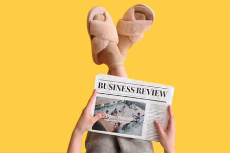 Young woman in soft slippers with newspaper on yellow backgroundの写真素材