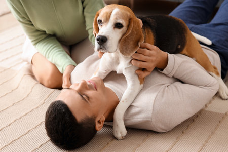 Young couple with cute Beagle dog at home, closeupの写真素材