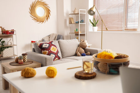 Knitted toy bear with yarn on sofa in living room interiorの写真素材