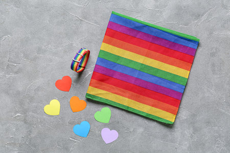 Paper hearts with bracelet and rainbow fabric on grunge background. LGBTQ concept