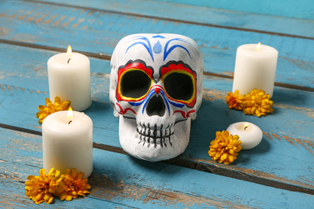 Painted skull with marigold flowers and candles on blue wooden background. Celebration of Mexico's Day of the Dead (El Dia de Muertos)の写真素材