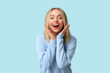 Beautiful happy young woman laughing on blue backgroundの写真素材