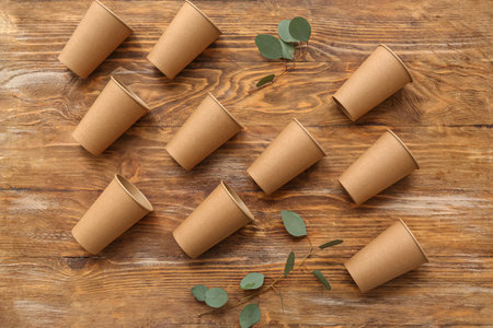 Eco cups with plant leaves on brown wooden backgroundの写真素材