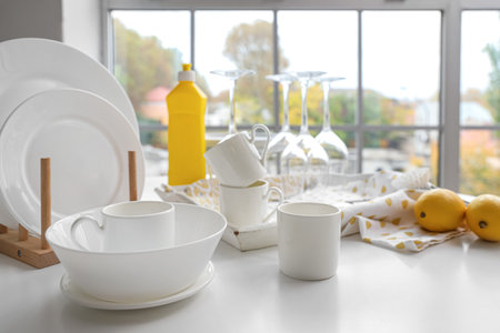 Set of white dishes with cleaning supplies and lemons on table in kitchenの写真素材