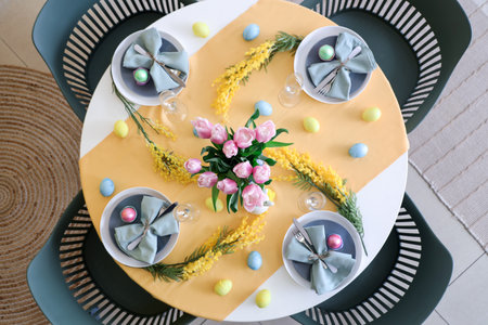 Easter table setting with mimosa flowers, painted eggs and tulipsの写真素材