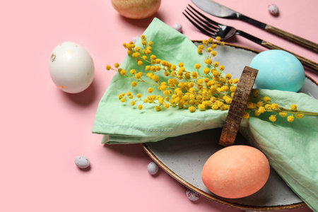 Beautiful table setting with Easter eggs on pink background