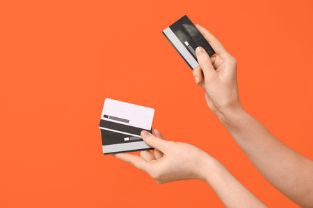 Female hands with credit cards on orange background