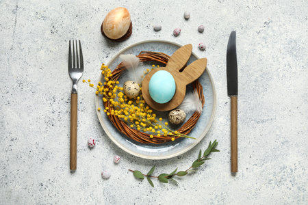 Beautiful table setting with Easter eggs and feathers on white background