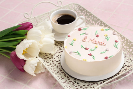 Sweet bento cake with cup of coffee and beautiful tulips on pink tile background. International...