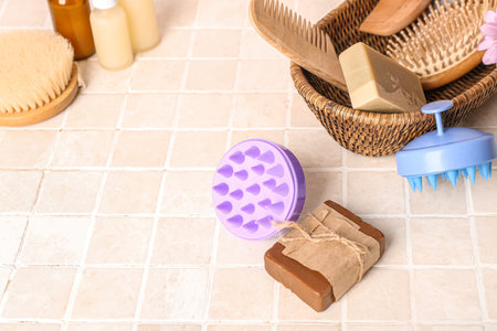 Hair scalp massagers with shampoo bars and bottle of cosmetic products on pink tile background