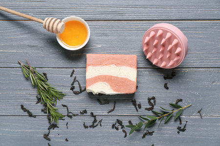 Hair scalp massager with shampoo bar and bowl of honey on gray wooden backgroundの写真素材