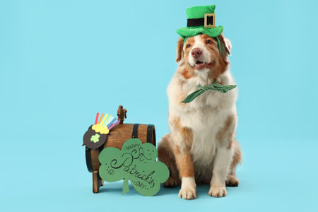 Cute Australian Shepherd dog in leprechaun's hat with card and barrel on blue background. St. Patrick's Day celebrationの写真素材