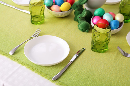 Festive table setting with Easter eggs on green tablecloth