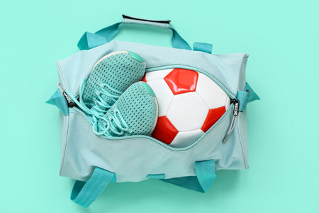 Sports bag with soccer ball and shoes on cyan backgroundの写真素材