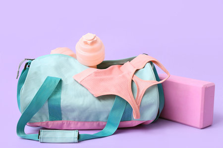 Sports bag with sportswear and dumbbells on purple backgroundの写真素材