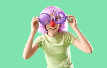 Funny little girl in disguise on green background. April Fools' Day celebrationの写真素材