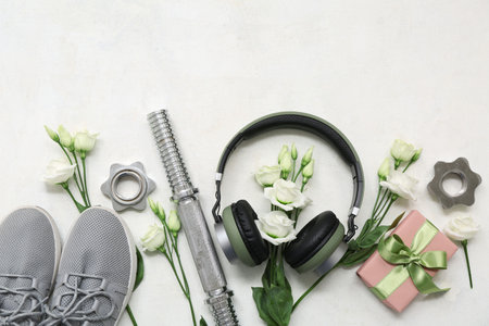 Composition with sports equipment, modern headphones, gift box and flowers on light background. International Women's Dayの写真素材