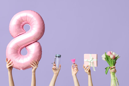 Female hands with foil balloon in shape of figure 8, sports equipment and tulips for International Women's Day on lilac backgroundの写真素材