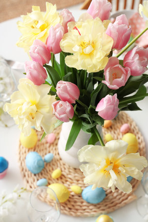 Vase of flowers on festive Easter table with painted eggs