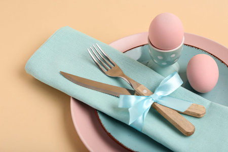 Beautiful table setting with pink Easter eggs on yellow background
