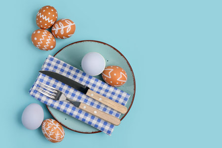 Beautiful table setting with Easter eggs on blue background