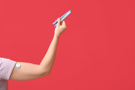 Woman's hand with lancet pens and glucose sensor on red background. Diabetes conceptの写真素材