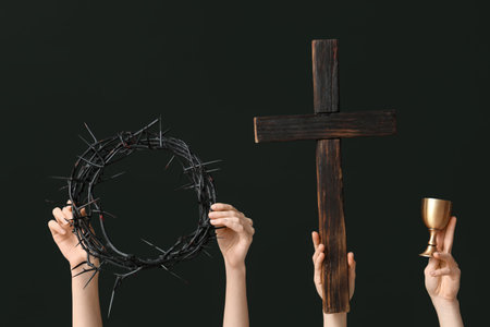 Female hands with crown of thorns, wooden cross and cup on dark background. Good Friday conceptの写真素材