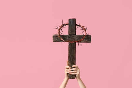 Female hands with wooden cross and crown of thorns on pink background. Good Friday conceptの写真素材