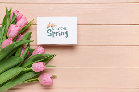 Greeting card with text WELCOME SPRING and beautiful tulips on pink wooden backgroundの写真素材