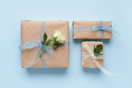 Gift boxes with beautiful white rose on blue background. International Women's Day