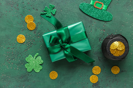 Gift box with pot of golden coins and decor for St. Patrick's Day celebration on green grunge...