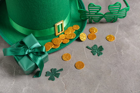 Gift box with leprechaun hat, plastic eyeglasses and decor for St. Patrick's Day celebration on gray...