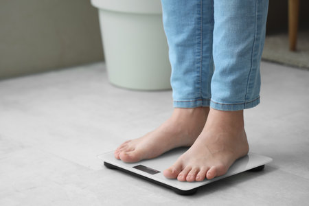 Young woman standing on scales at home. Weight loss conceptの写真素材
