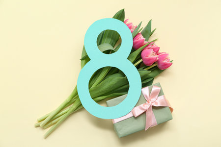 Figure 8 made of paper with gift box and bouquet of beautiful tulips on yellow background....
