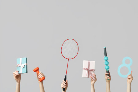 Female hands with paper figure 8, sports equipment and gifts for International Women's Day on gray backgroundの写真素材