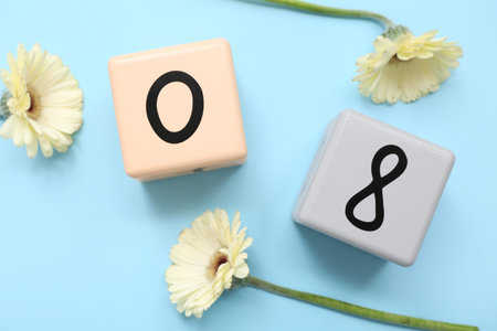 Cube calendar with date of International Women's Day and beautiful flowers on color background