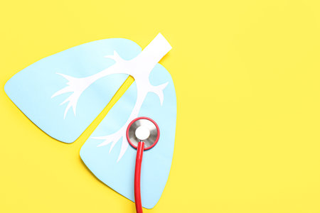 Paper lungs with stethoscope on yellow background
