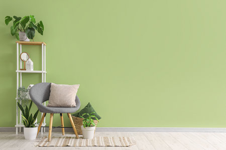 Interior of living room with armchair, cushion and houseplants near green wallの写真素材