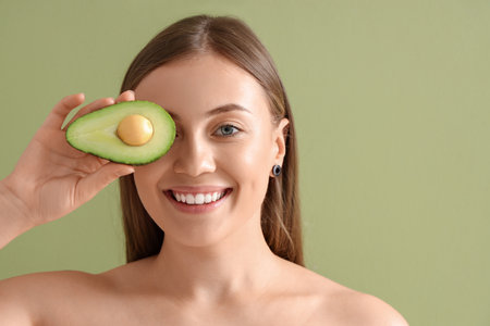 Beautiful woman with avocado on green background, closeupの写真素材