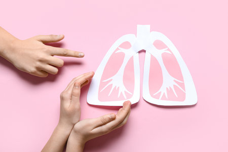 Hands of woman and child with paper lungs on pink backgroundの写真素材