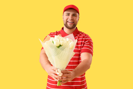 Delivery man with flowers on yellow backgroundの写真素材